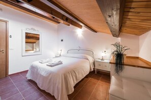 Cozy retreat with a single bed, bedside tables, and a mirror, set against a sloping ceiling with wooden beams.