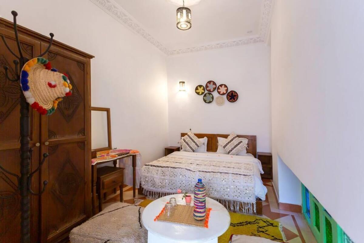 A bedroom with a bed, bedside table, lamp, and decorative items.