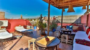 A rooftop terrace with a thatched roof, outdoor seating, and a view of the cityscape. - Riad Rose Meryam (Marrakech)