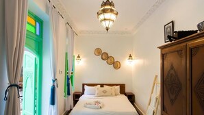 A hotel room with a bed, a wooden wardrobe, a ladder, and a wall-mounted light fixture. - Riad Rose Meryam (Marrakech)