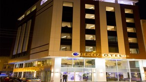 Un hotel moderno con un llamativo letrero que dice 'EMIN HOTEL', ventanas amplias y una entrada bien iluminada.