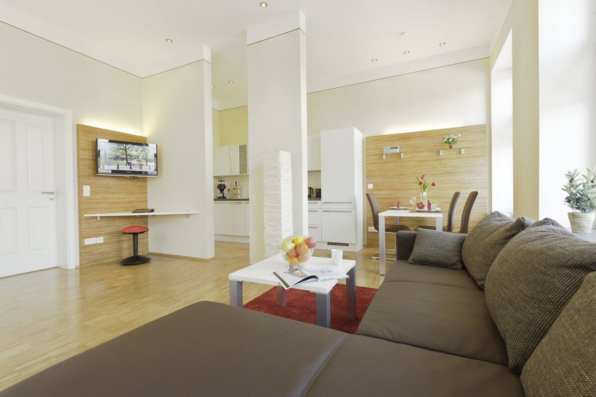A modern living room with a sofa, coffee table, and a TV mounted on the wall.
