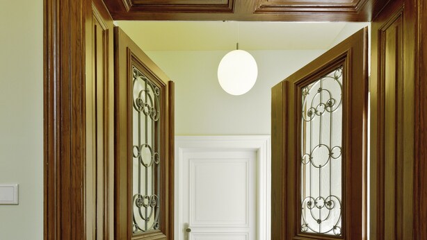 Un couloir avec des portes en bois et une porte blanche au bout.
