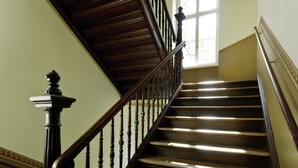 Un escalier en bois, doté d’une balustrade, menant à un palier avec une fenêtre.