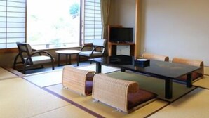 Una habitación con esteras de tatami, una mesa baja, sillas y un televisor.
