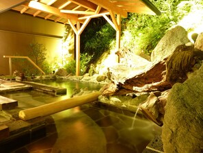 A traditional Japanese onsen with a wooden structure, a hot spring bath, and surrounding rocks and plants. - Kameya Ean (Izunokuni)