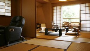 Una habitación japonesa tradicional con suelo de tatami, una silla de masaje negra y techo de madera.