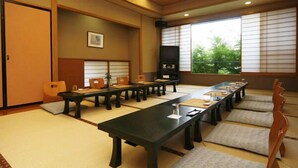 Una sala de reuniones tradicional japonesa con esteras de tatami, una mesa larga y sillas de madera.