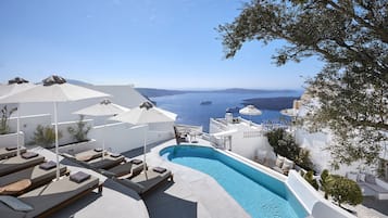 Una piscina al aire libre, sombrillas, sillones reclinables de piscina