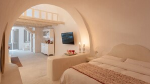 A bedroom with a bed, a nightstand, a TV, and a window. - Senses Suites (Santorini)