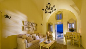 A cozy living room with a sofa, coffee table, and dining area. - Senses Suites (Santorini)