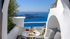 A terrace with a table set for two, overlooking a scenic view of the sea and islands. - Senses Suites (Santorini)