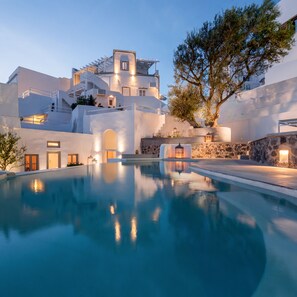 Un hotel moderno con piscina, arquitectura blanca y paredes de piedra.