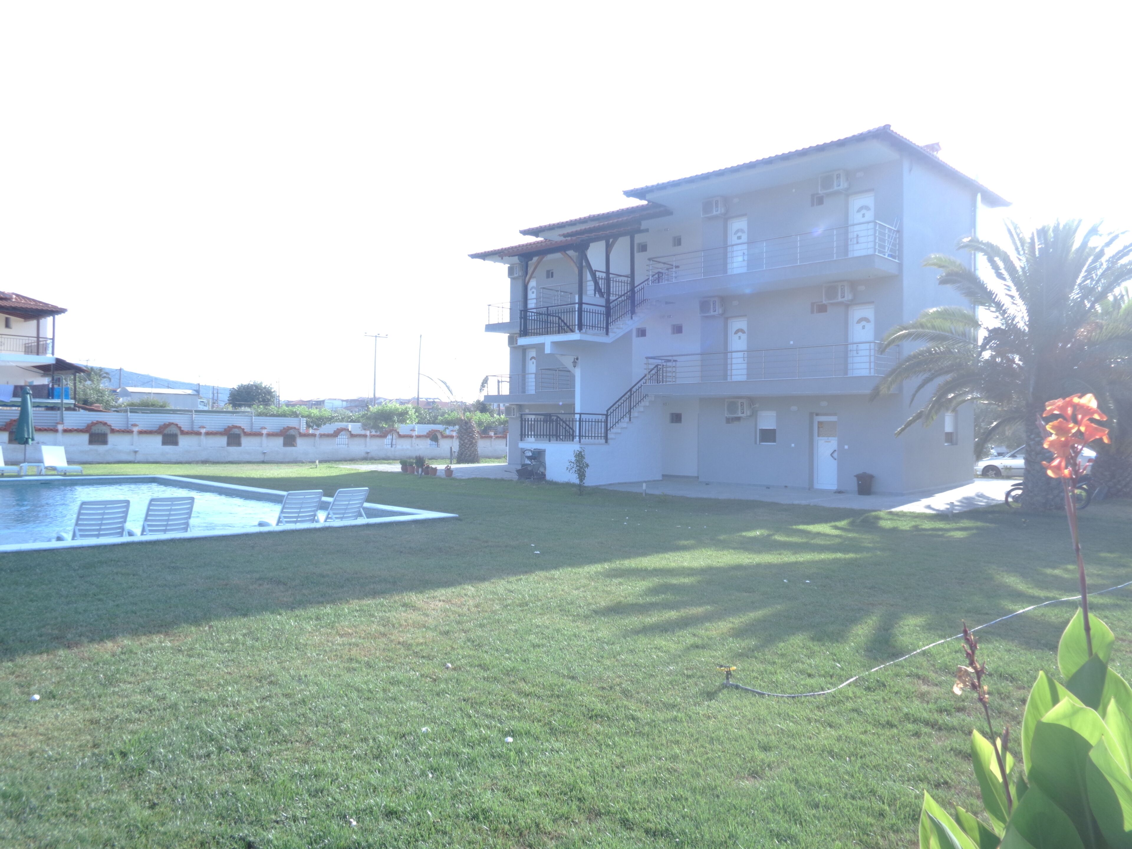 A multi-story building with a pool and a grassy area.