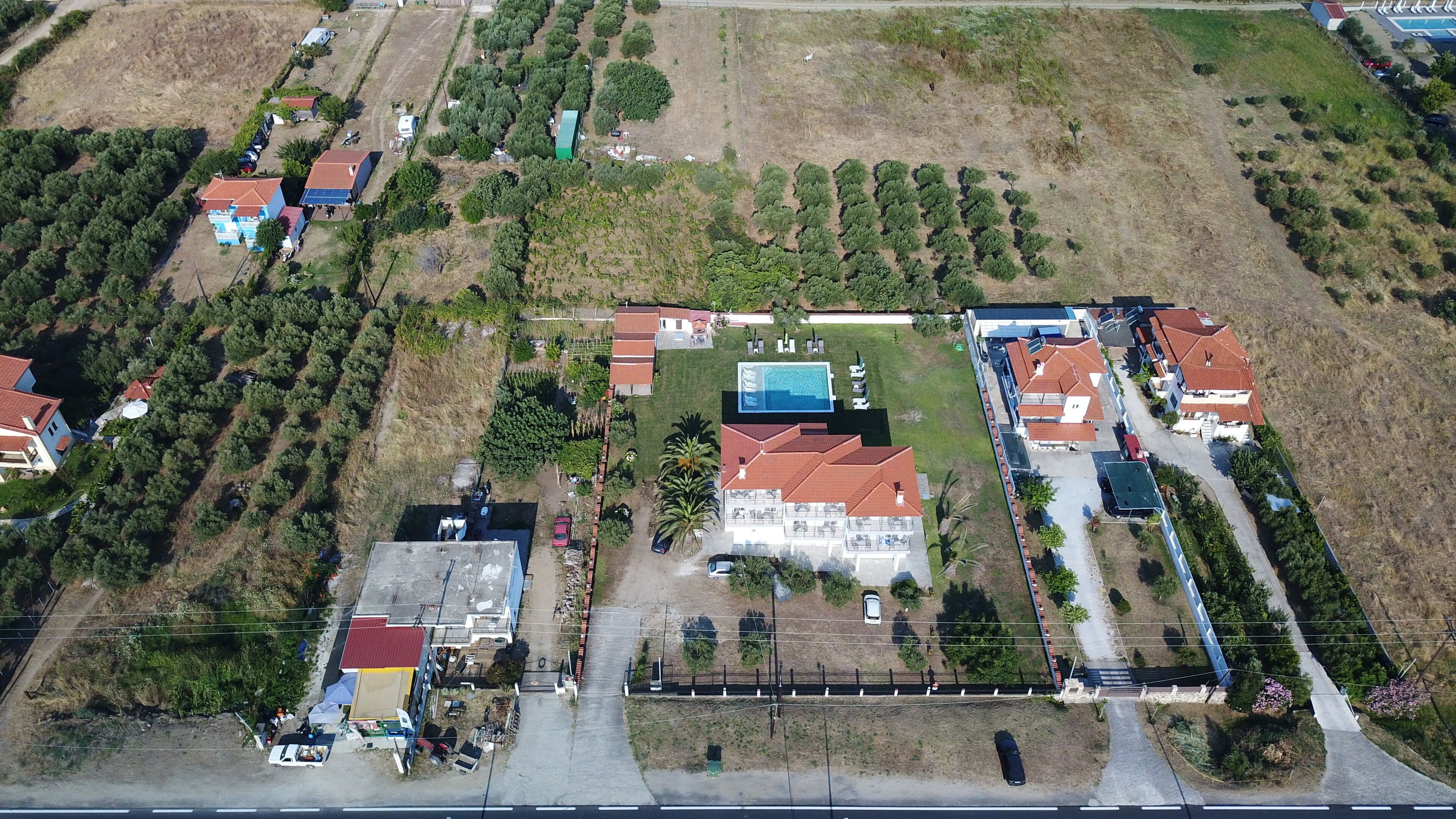 An aerial view of a residential area with houses, a swimming pool, and a road.