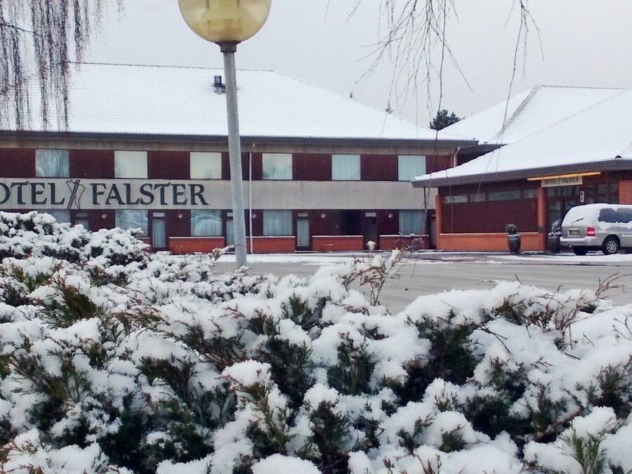 A hotel named "HOTEL FALSTER" with a snow-covered roof and a parked car in front.