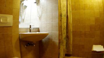 A bathroom with a toilet, sink, and shower area.
