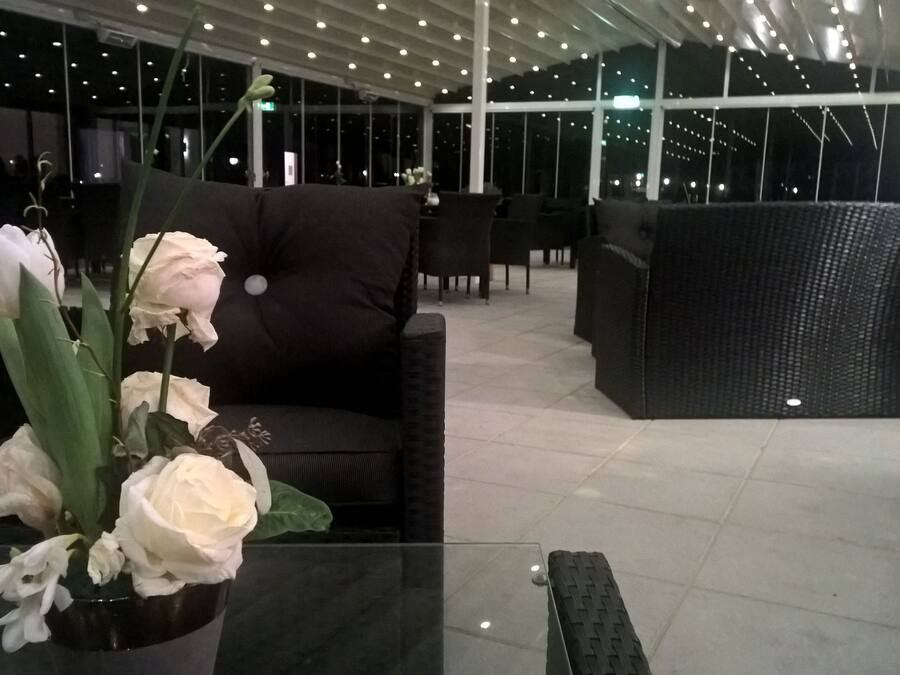 Ein moderner Lounge-Bereich mit schwarzen Sofas und einem Glastisch mit einer Vase weißer Blumen.