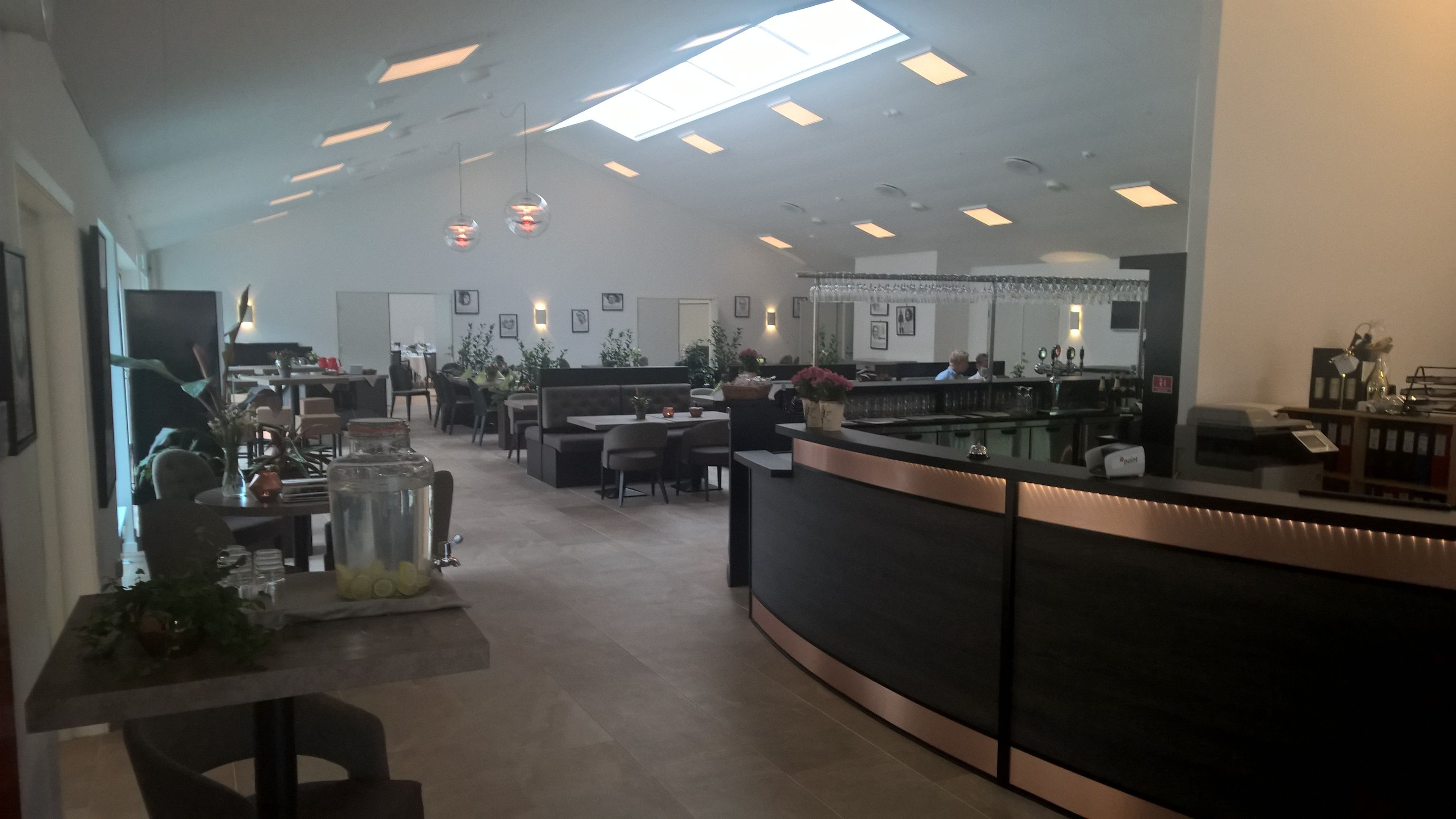 A spacious hotel lobby with a curved reception desk, seating areas, and a large window providing natural light.