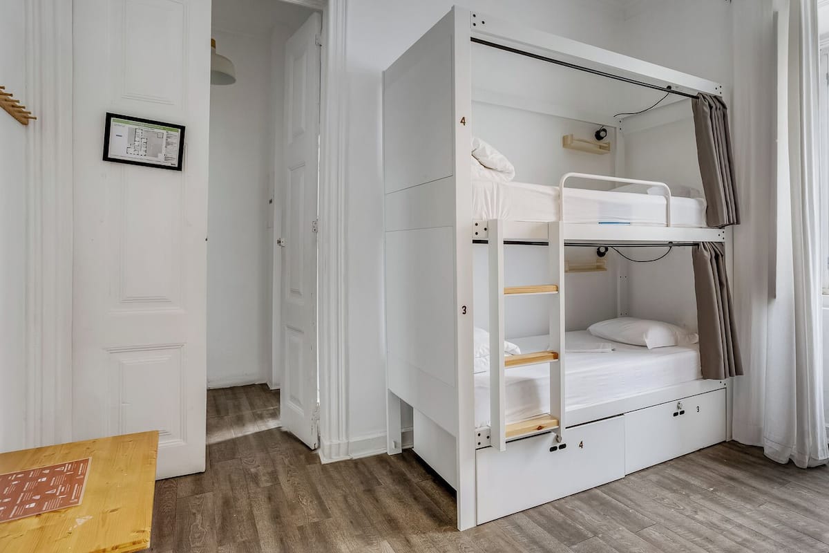 A room with a bunk bed, a wooden table, and a window.