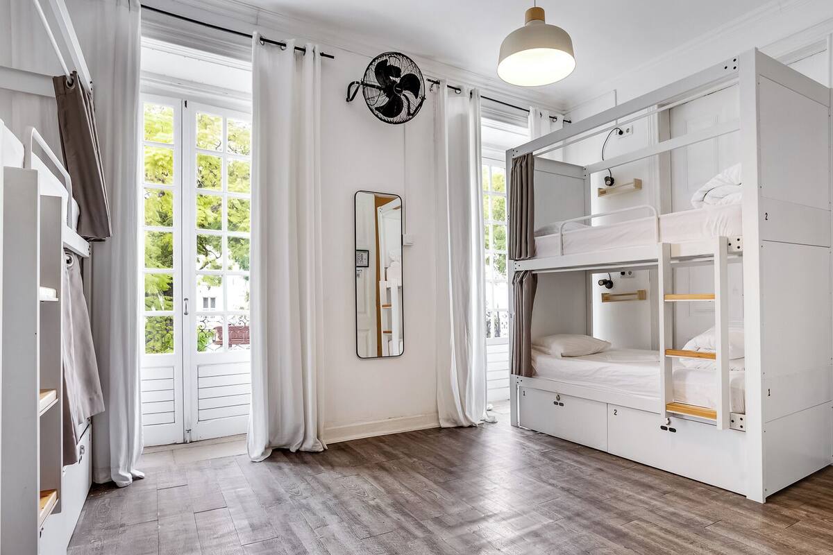 A room with bunk beds, a large mirror, and a fan.