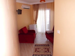 A narrow hallway with a red sofa, a white radiator, and a patterned rug. - Zeus Hotel (Silifke)