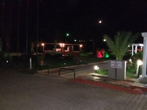 Vista nocturna de un edificio con mesas al aire libre y un letrero que indica que es un restaurante.