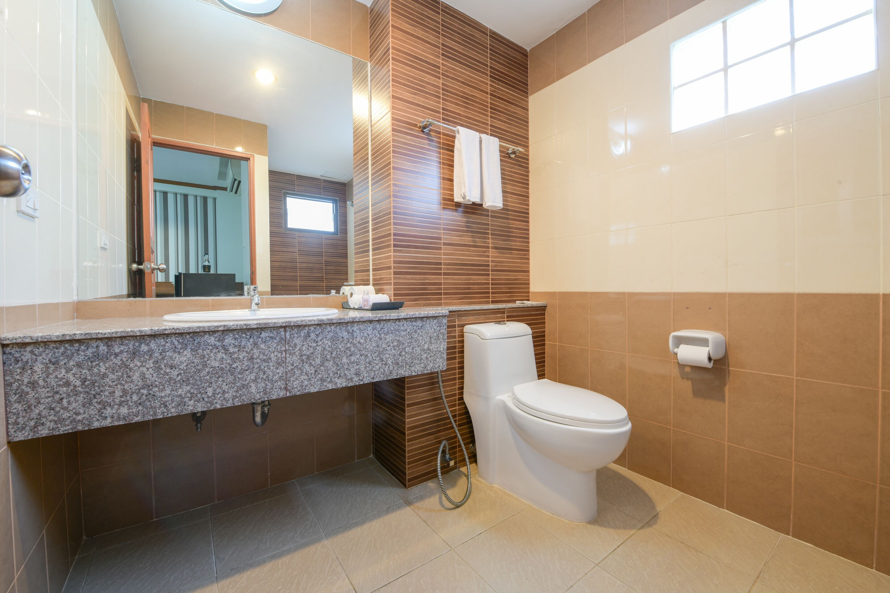Un baño moderno con encimera de granito, inodoro y espejo.