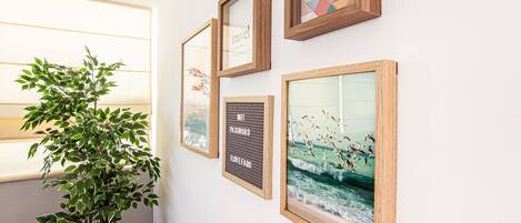 A wall with framed artwork and a potted plant.