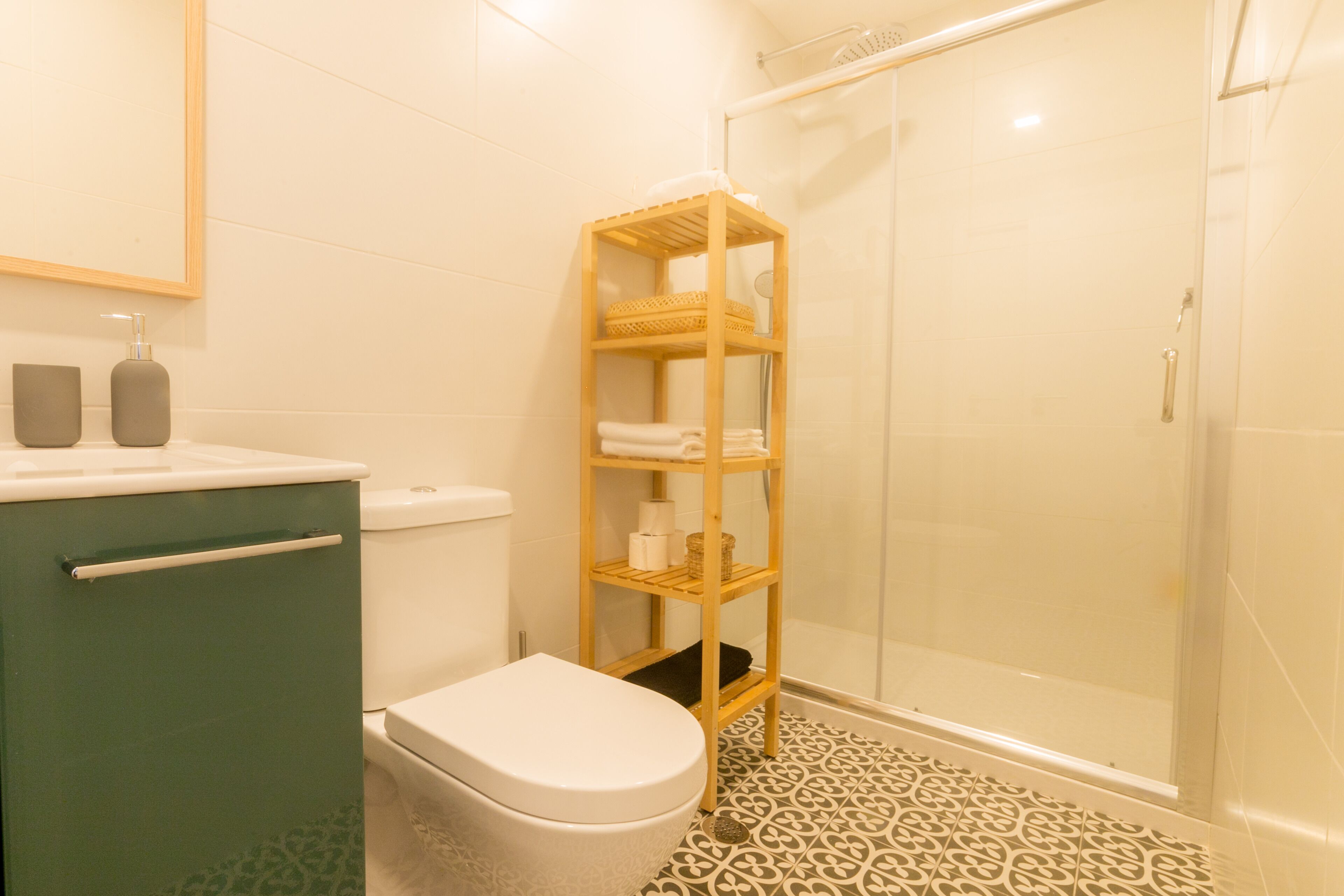 Une salle de bain comprenant des toilettes, une étagère avec des serviettes et un espace douche.