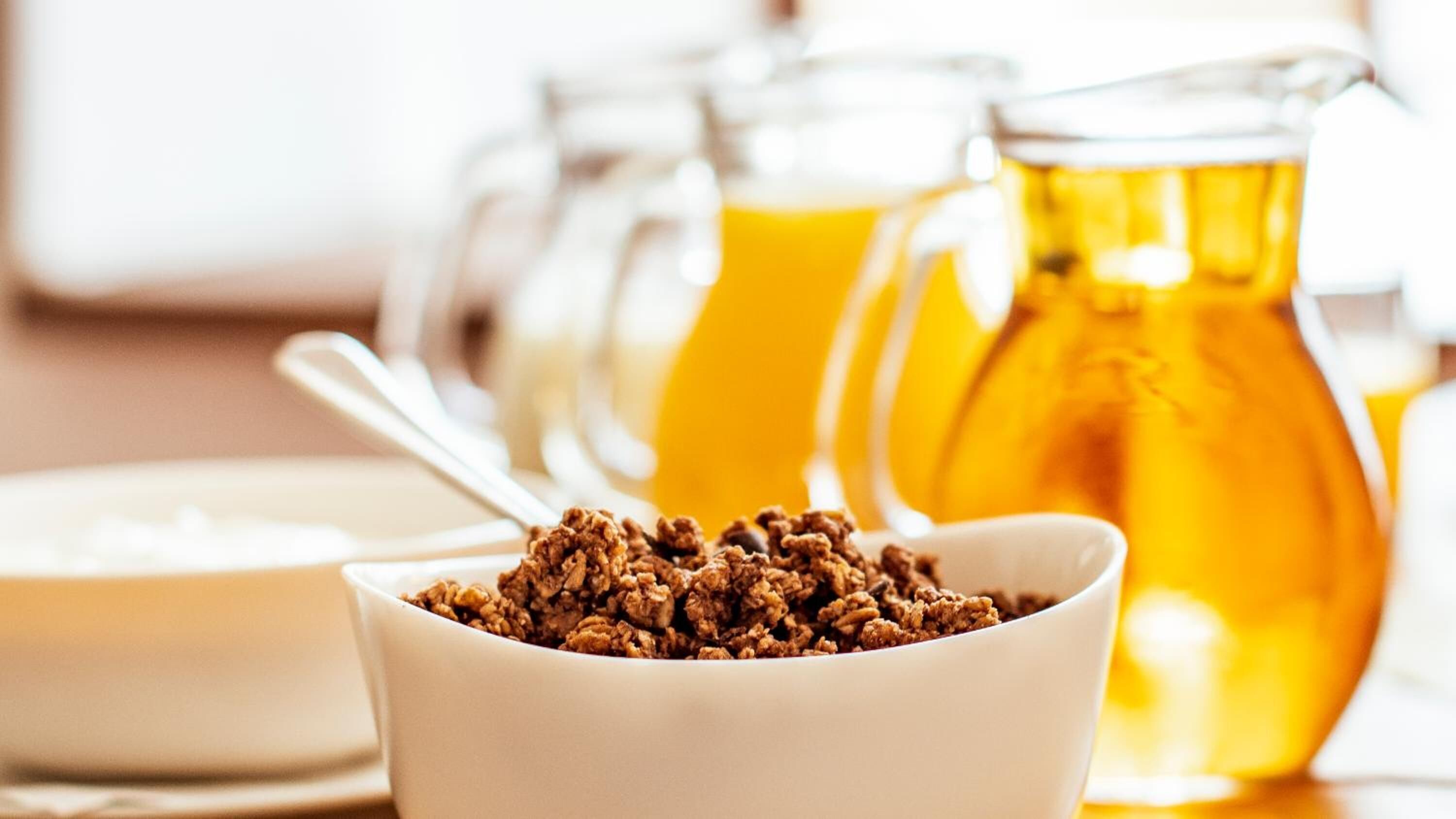 A bowl of granola with honey jars in the background.