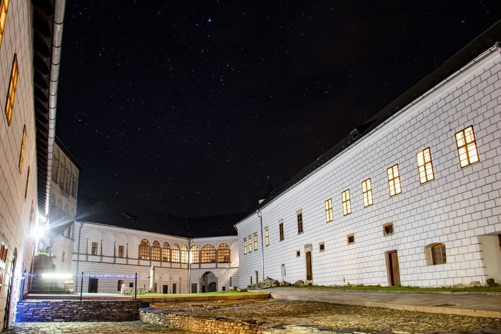 A courtyard with white brick buildings, stone walls, and a clear night sky.