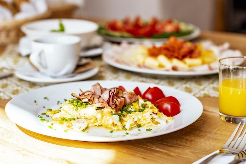 A breakfast setting with plates of food, cups, and a glass of orange juice on a table.