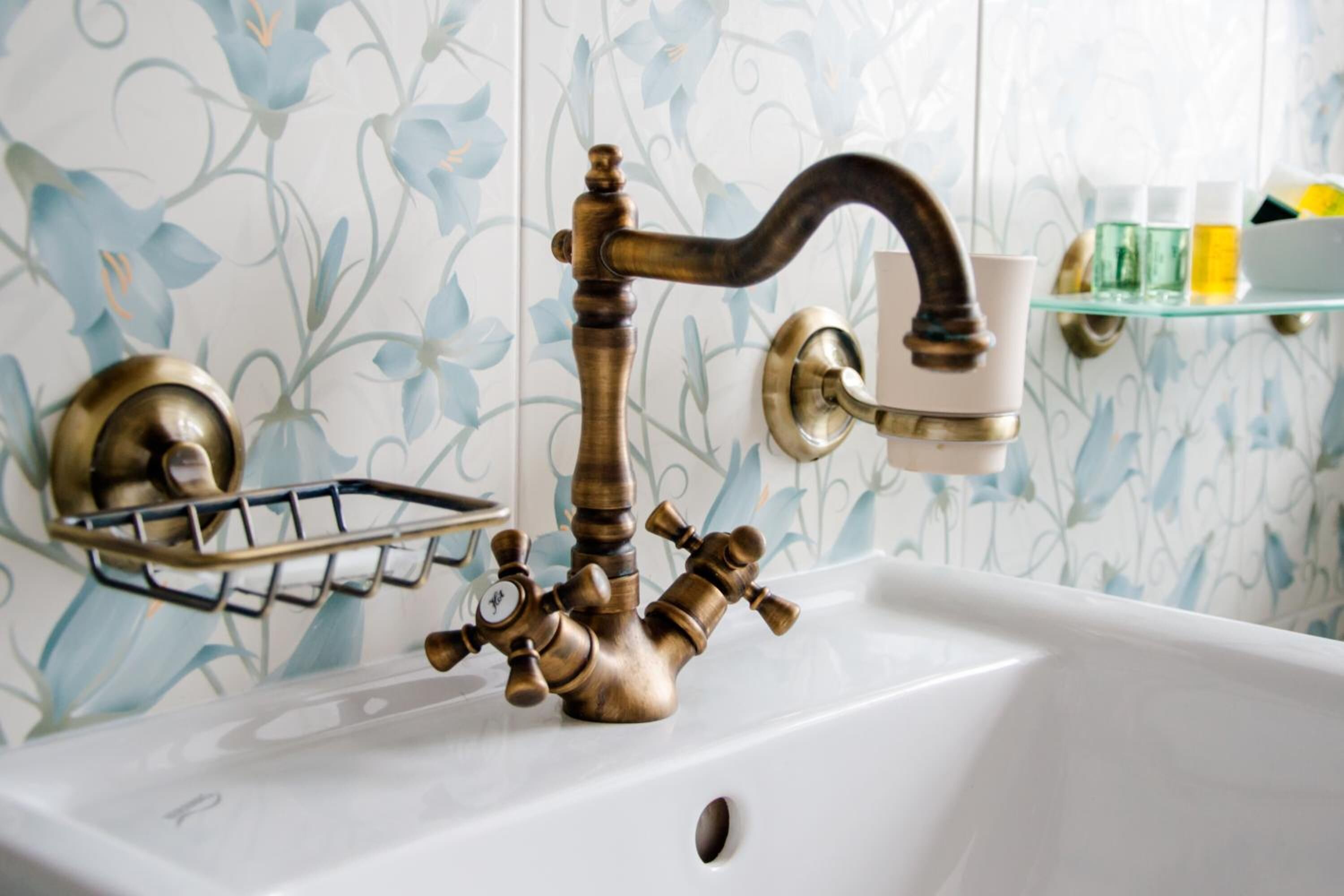 A bathroom sink with a brass faucet and a soap dish.