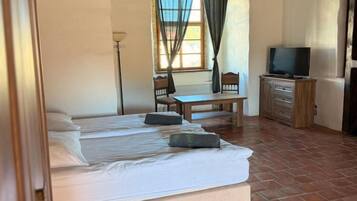 Un dormitorio con dos camas, un escritorio, una silla, un televisor y un aparador.