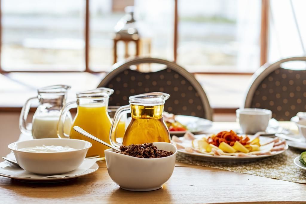 Un desayuno con una mesa, una jarra de jugo de naranja, un tazón de cereal y un plato de fruta y tocino.
