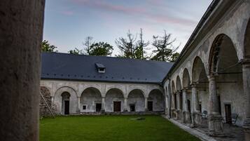 A courtyard with a building featuring arched walkways and a grassy area.