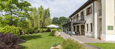 Un hotel con zona de estar al aire libre techada, una recepción y un césped bien cuidado.