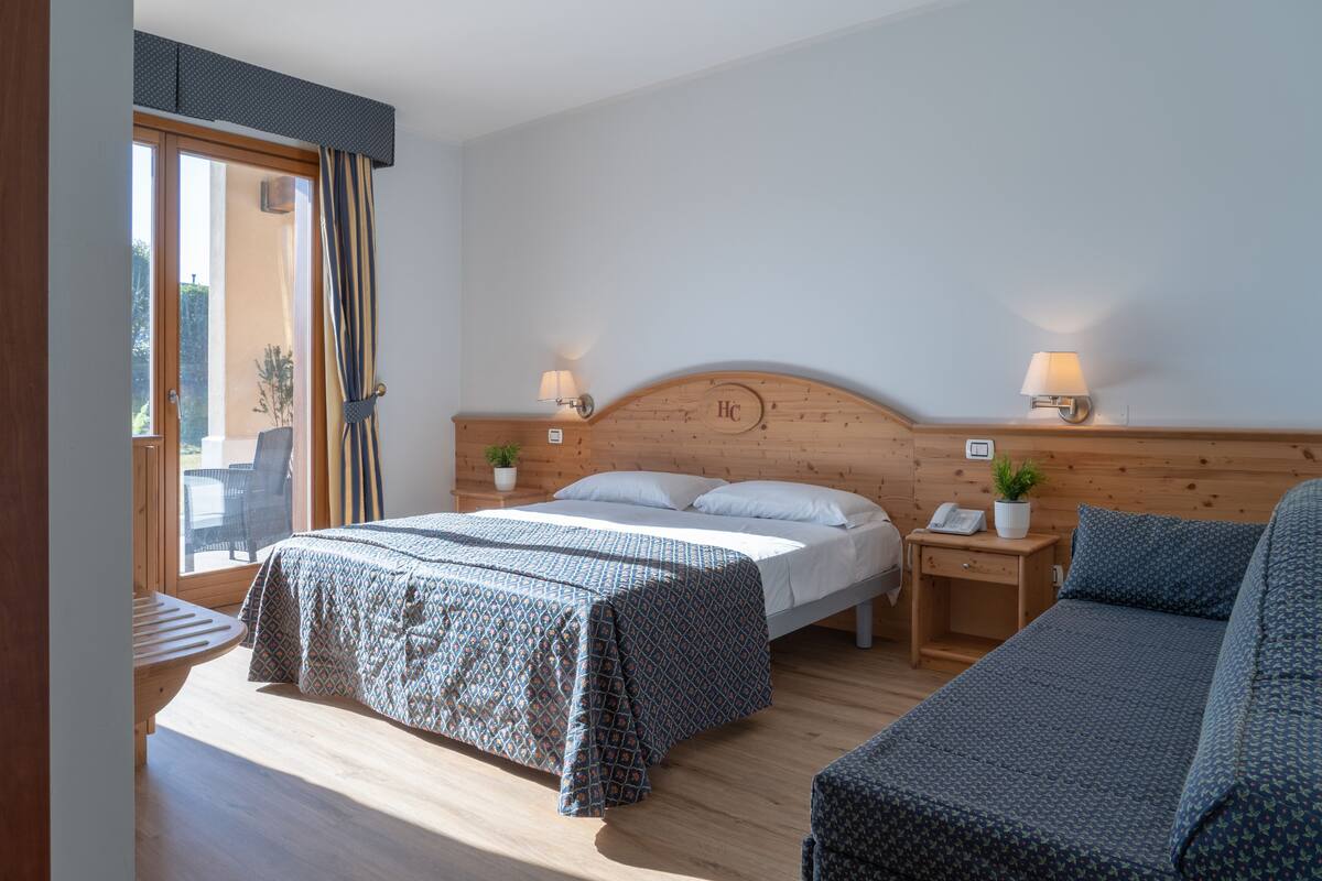A bedroom with a bed, bedside tables, a lamp, and a view through a window.