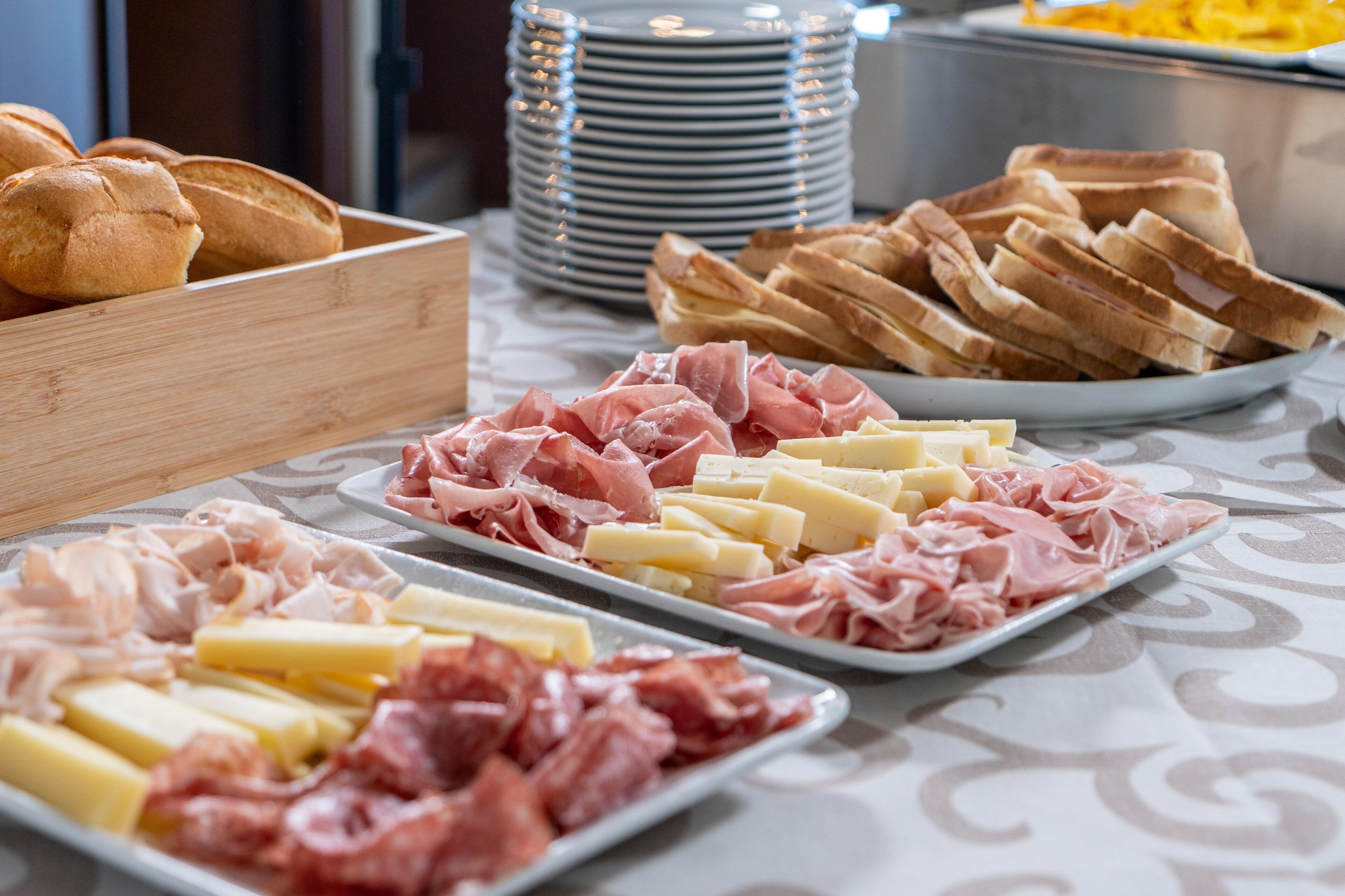 A buffet with various food items including meats, cheeses, and bread.