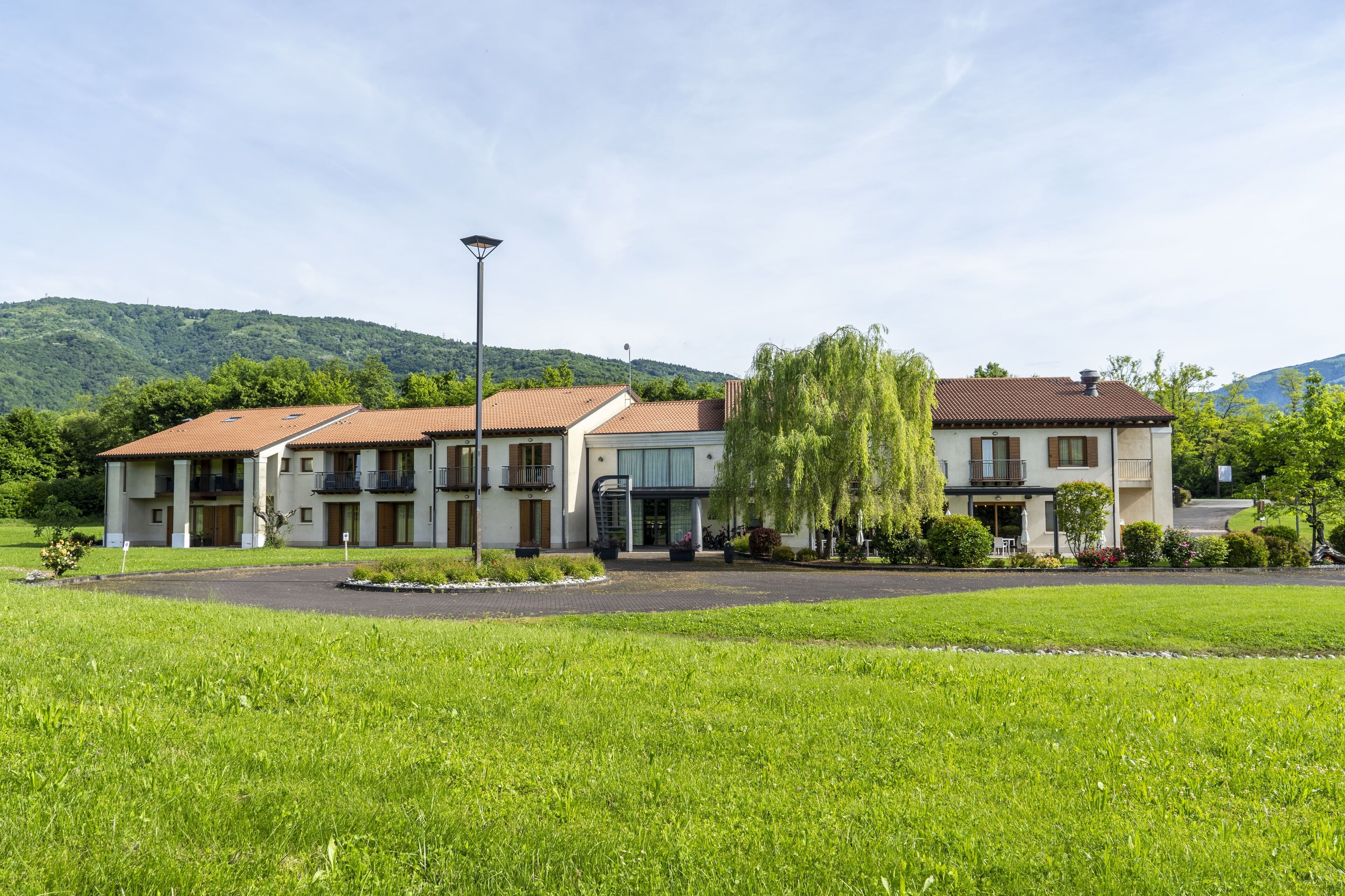 A hotel with a central courtyard, multiple balconies, and a mountain backdrop.