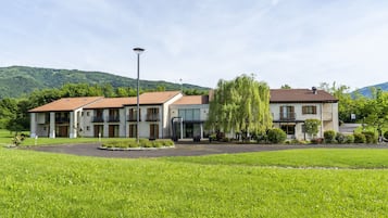 A hotel with a central courtyard, multiple balconies, and a mountain backdrop.