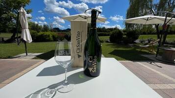 Una botella de vino y una copa sobre una mesa al aire libre, bajo un cielo despejado.