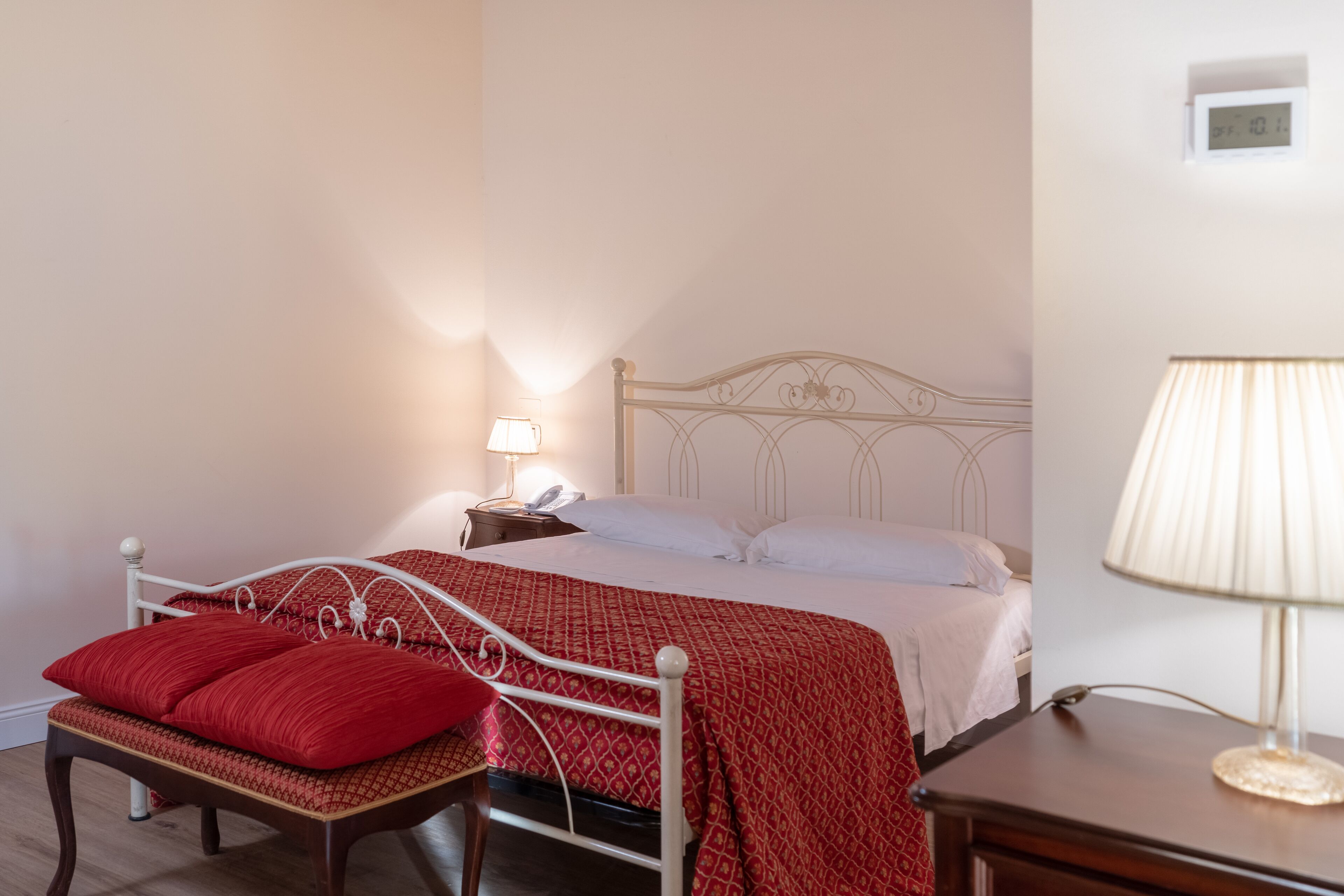 A bedroom with a bed, bedside table, lamp, and a chair.