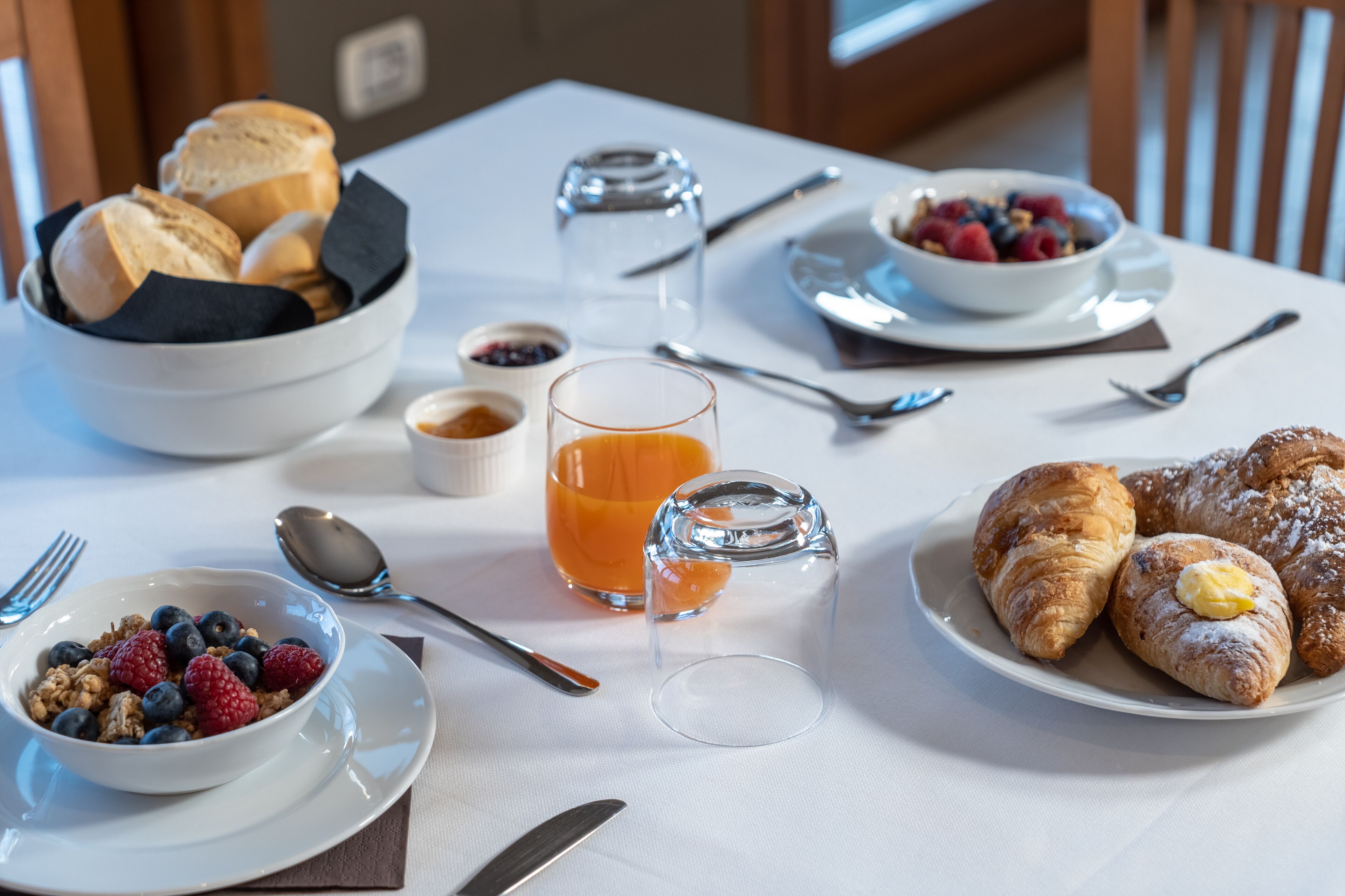 Una colazione servita con diversi cibi e utensili su un tavolo.