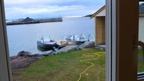 Vista de un puerto con barcos amarrados, un área verde y un edificio de fachada de madera.