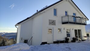 A two-story hotel with a balcony, a sign indicating it is an "Appart-Hotel Harmony," and a view of snow-covered hills in the background. - Appart-Hotel Harmonie (Winterberg)