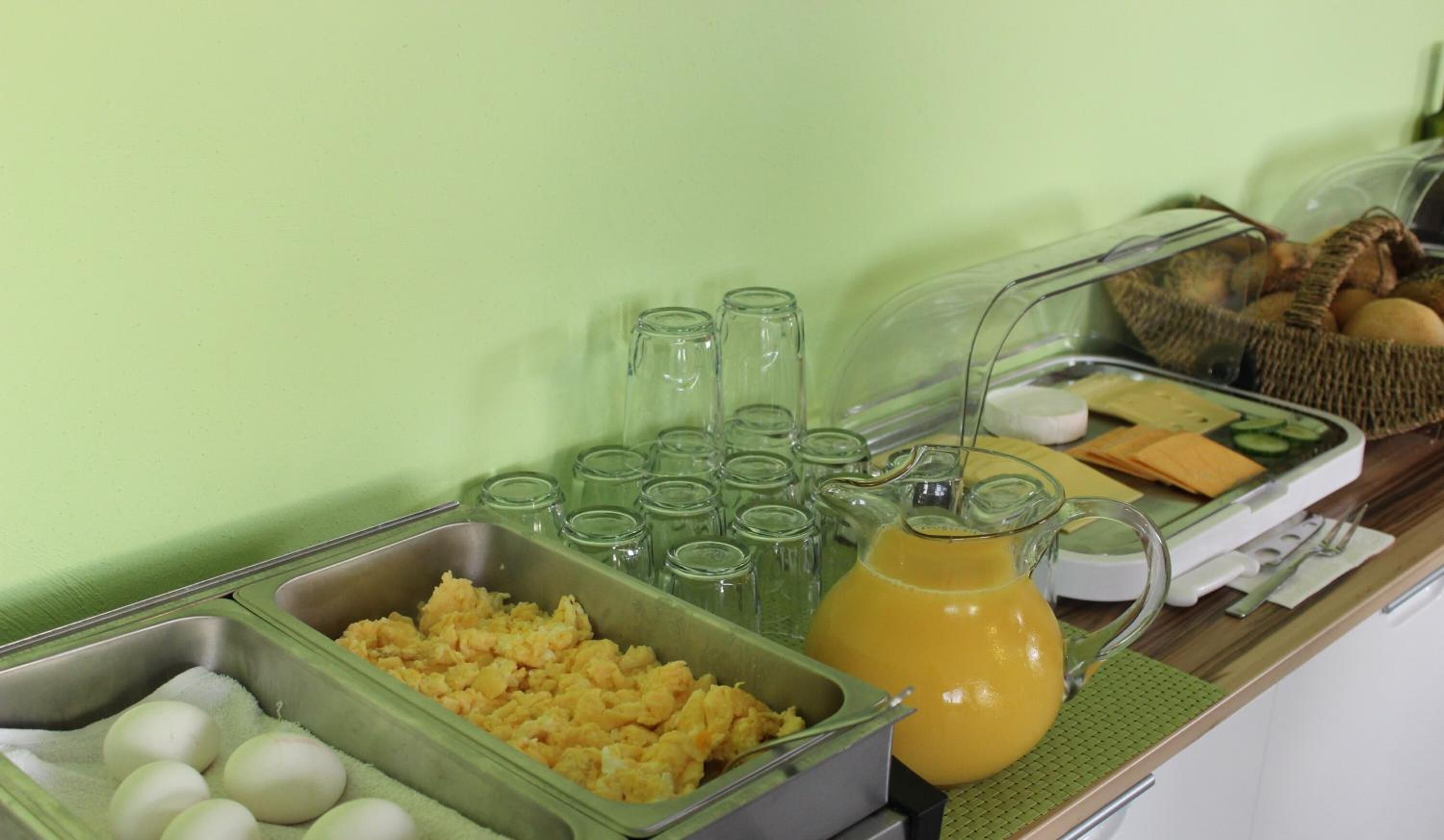 A breakfast buffet with scrambled eggs, a pitcher of orange juice, and various breakfast items.