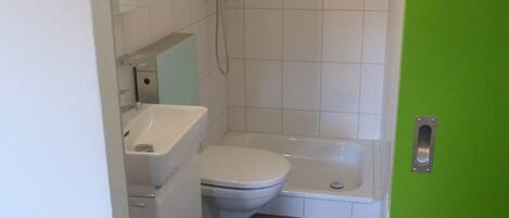 Un baño con inodoro, lavamanos, ducha y bañera.