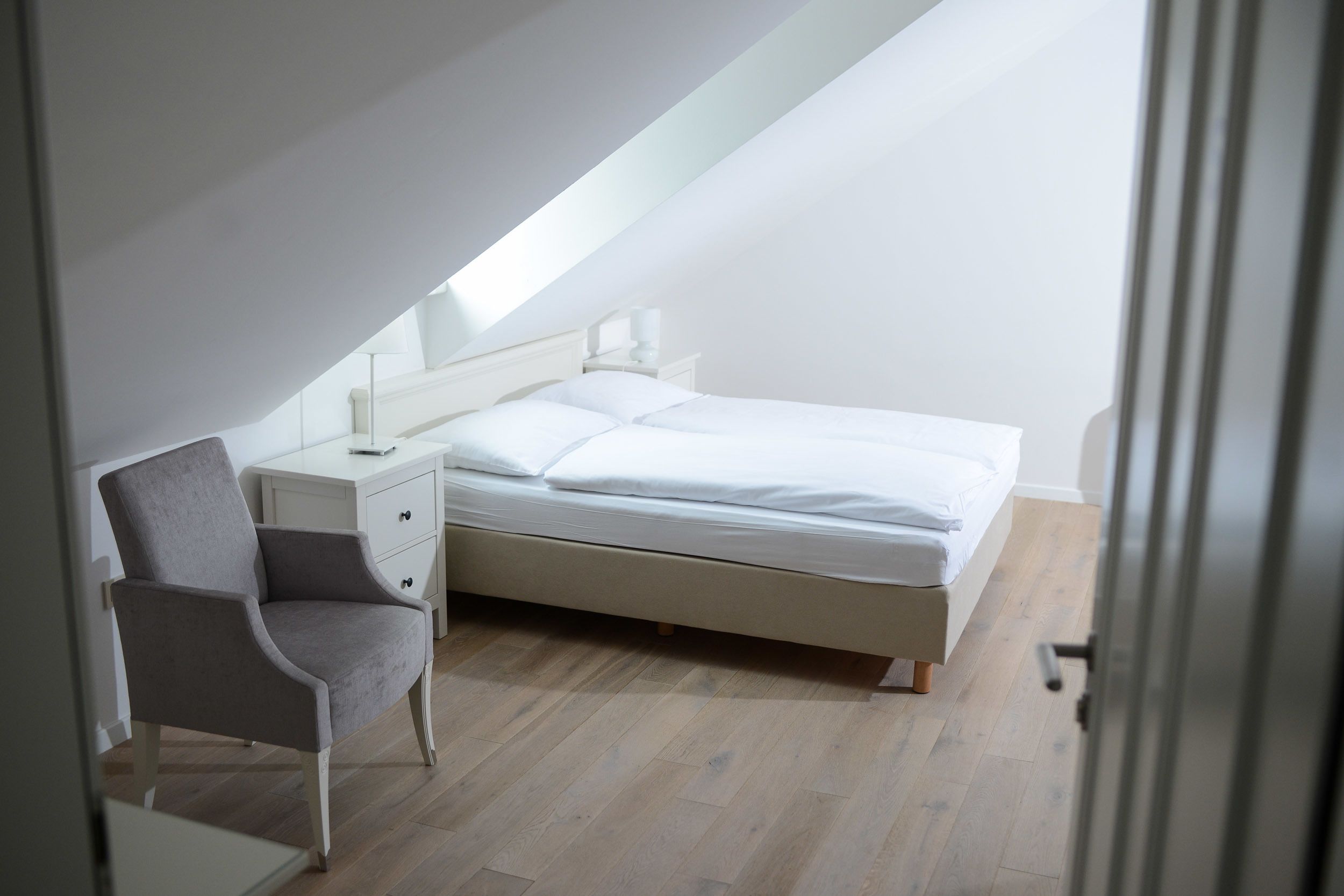 A bedroom with a bed, a chair, a nightstand, and a desk.